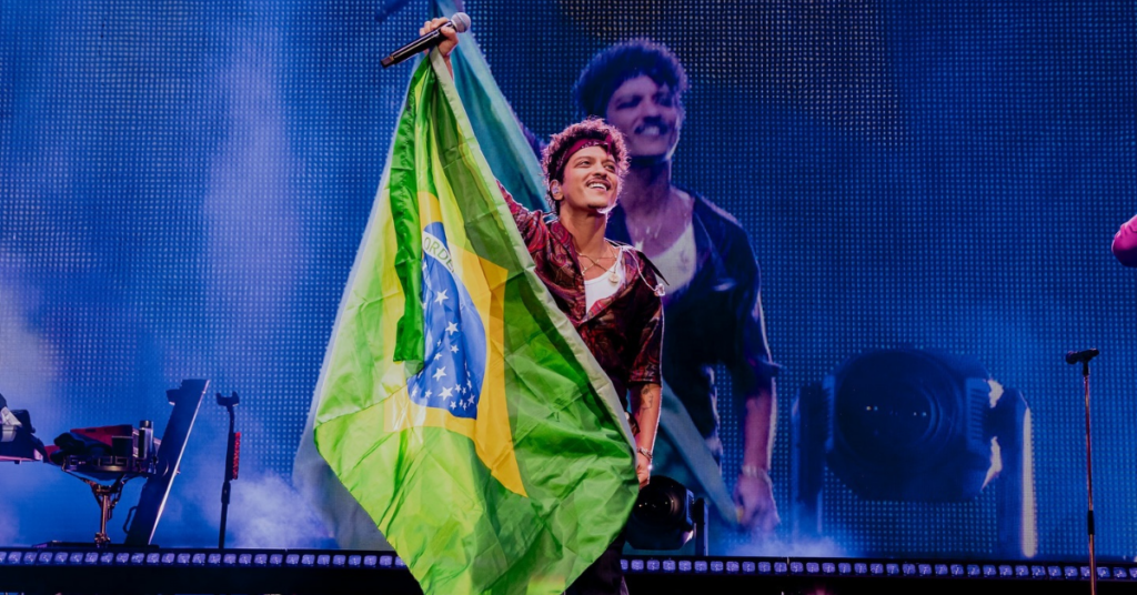 Bruno Mars segurando a bandeira do Brasil em passagem com sua turnê pelo país