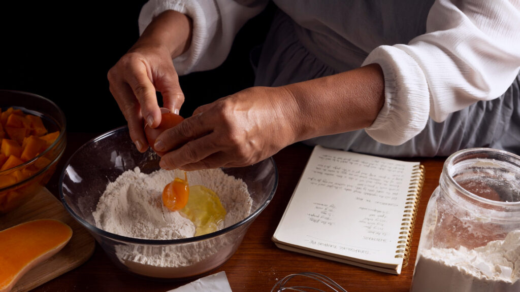 Mãos fazendo receita com ovos e farinha