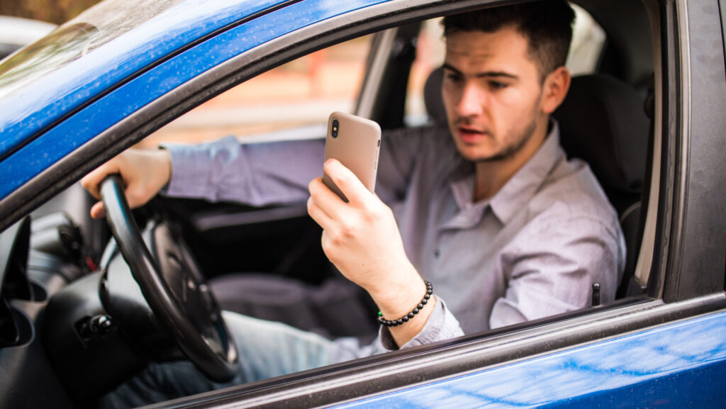 motorista mexendo no celular ao volante