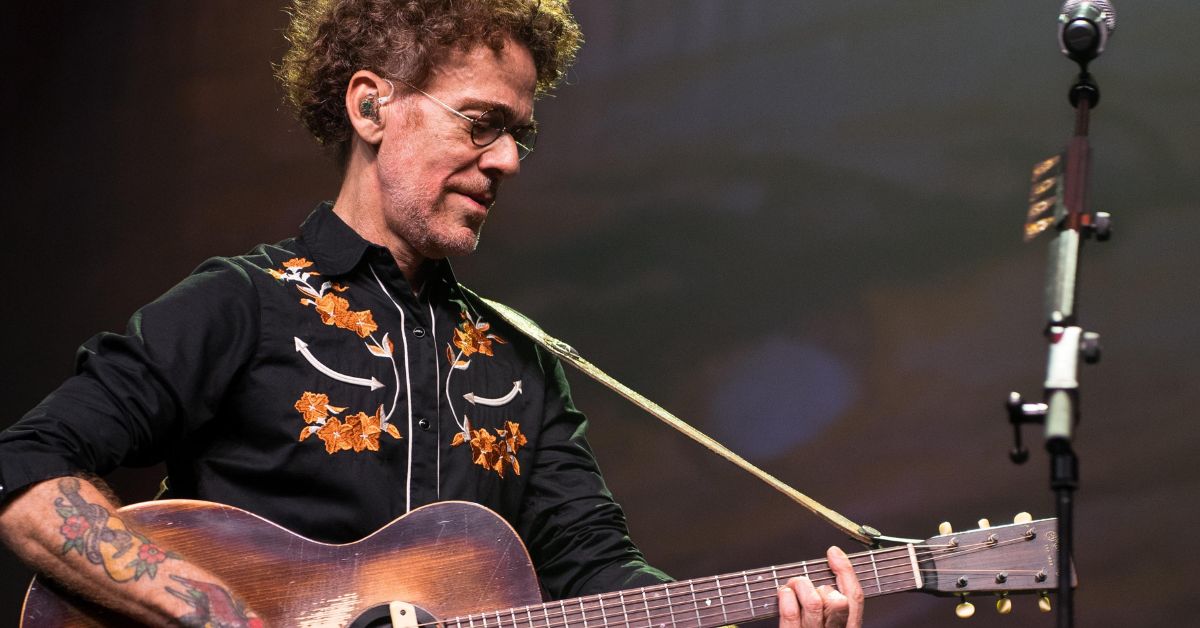 Nando Reis tocando violão durante um show.