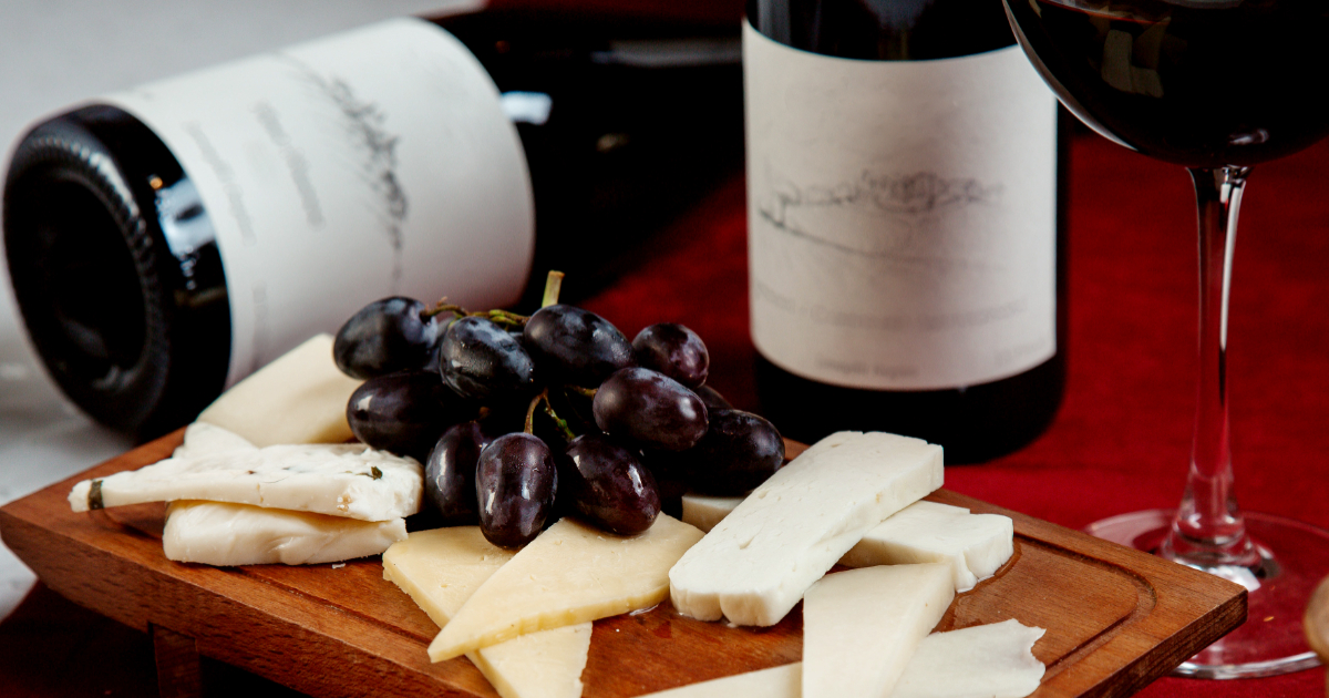 tábua de queijos e garrafas de vinho