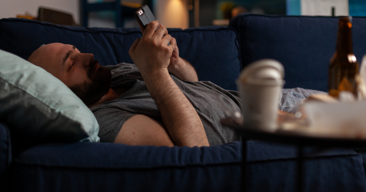 pessoa deitada no sofá e mexendo no celular