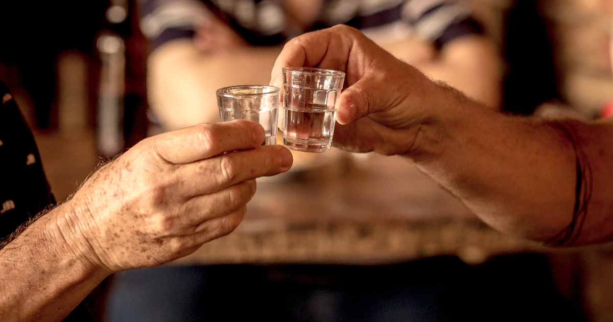 pessoas brindando com dose de cachaça