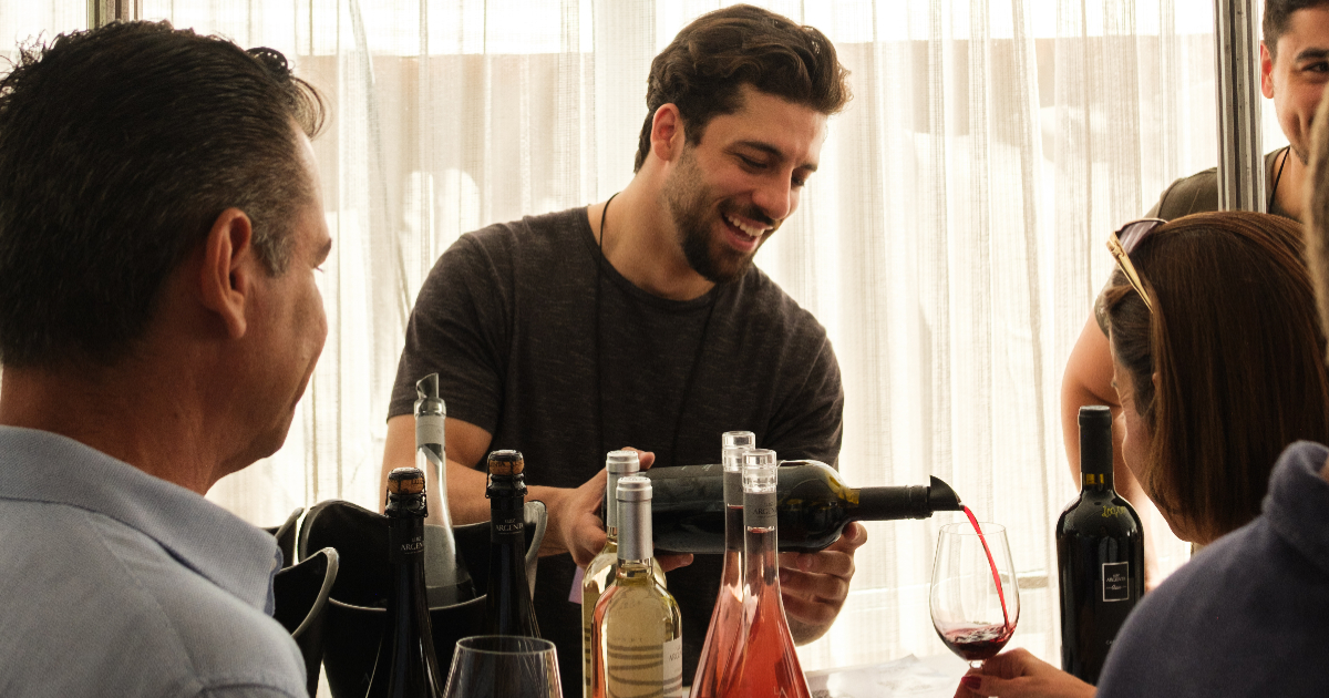 pessoa servindo taça de vinho tinto para outra