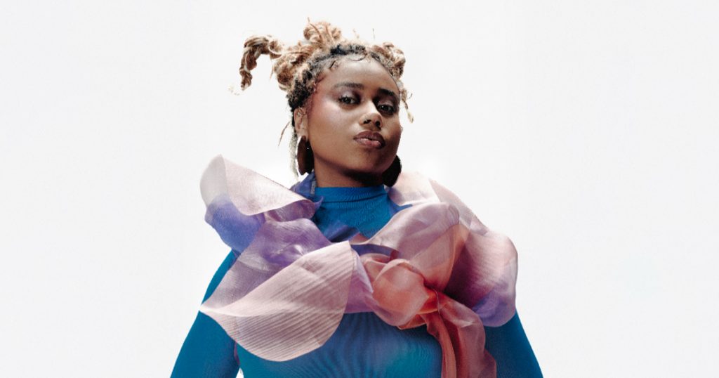 melly posando com expressão séria e casaco azul para as fotos de divulgação do álbum mais forte que a dúvida