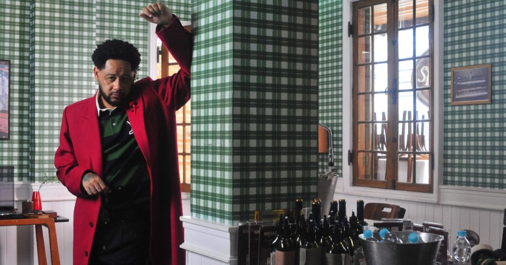 emicida posando em uma cozinha e vestindo um casaco vermelho