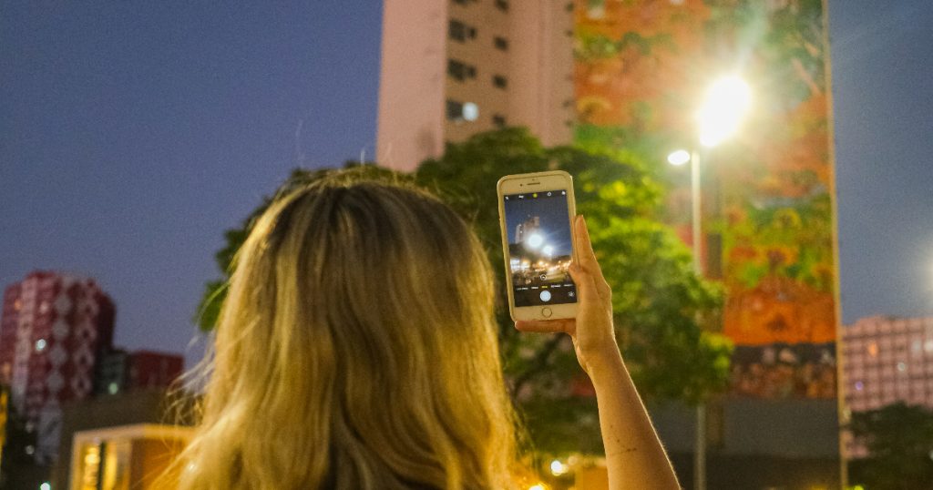 pessoa apontando a câmera de um celular para um prédio em belo horizonte