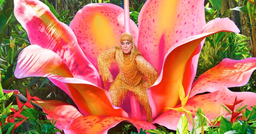ney matogrosso com roupa dourada dentro de uma flor cenográfica gigante