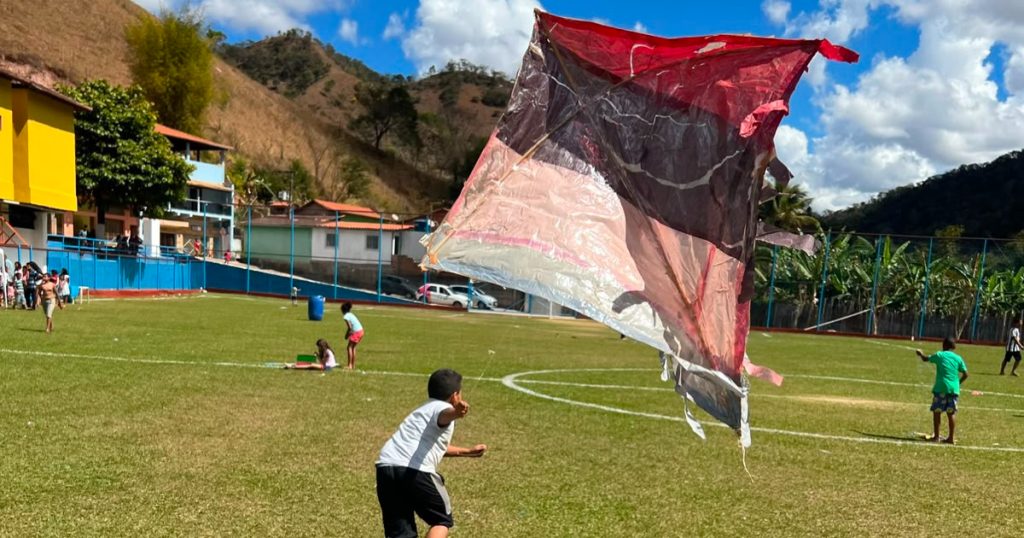criança soltando pipa em um campo
