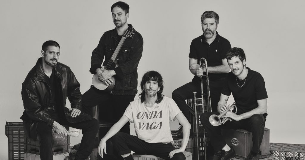 banda onda vaga sentada em caixotes e posando com instrumentos musicais