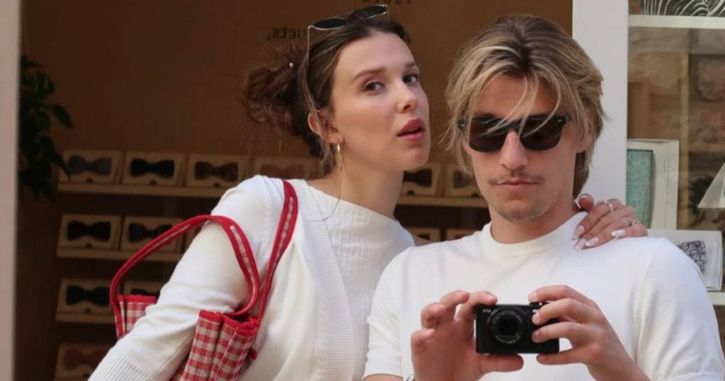 millie bobby brown e jake bongiovi posando juntos com câmera analógica