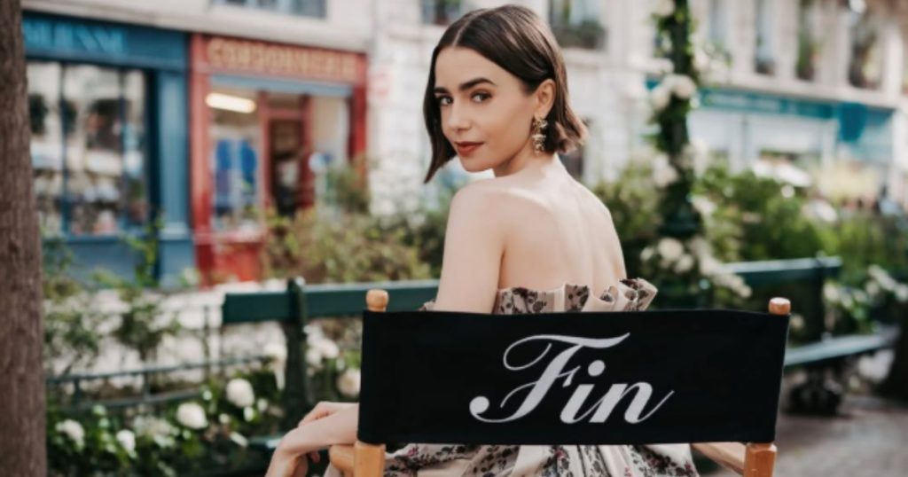 lily collins sentada em uma cadeira de direção no set de emily em paris
