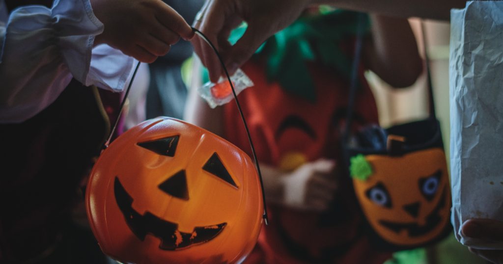 pessoa colocando um doce em um pote de halloween